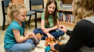 Photo of two young girls playing with toys while sitting on the floor