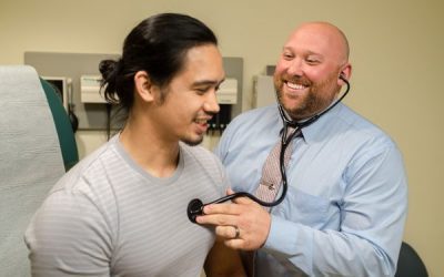 Imagine a unui medic de sex masculin care ascultă bătăile inimii unui bărbat adult cu un stetoscop